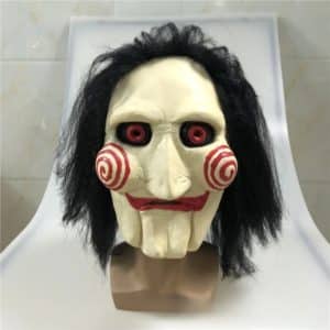 Masque de Saw avec les yeux rouges, cheveux noirs et des cercles sur les joues posé sur un support
