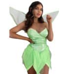 Une femme pose dans un déguisement de fée clochette. Il est composé d'ailes blanches et vertes et d'une robe verte avec un haut ajusté et d'un bas en forme de pétales de fleurs.