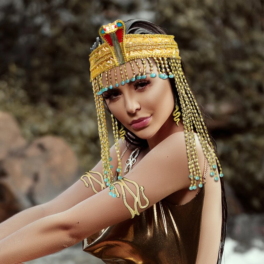 Femme portant le bijou de tête de la reine Cléopâtre, un bandeau ajustable doré avec des mèches de perles à la façon d'une perruque, chaque mèche terminée par une perle bleue. Le bandeau est orné d'une tête de cobra et le modèle est sur fond de nature.