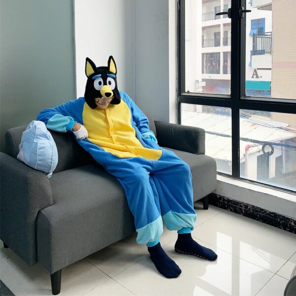 Homme assis sur un canapé portant le costume de chien bleu et jaune pour adulte, se composant d'une combinaison à enfiler avec une capuche à tête de chien.