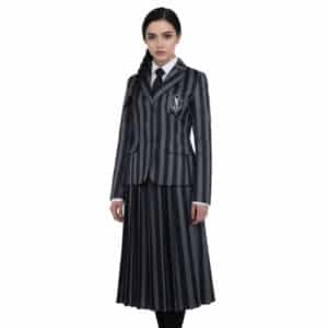 Une fille brune portant un déguisement Famille Addams, uniforme de Mercredi noir et gris avec l'insigne de Nevermore, sur un fond blanc uni.