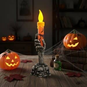 Bougie orange pour Halloween avec un design de squelette posée sur une table avec des citrouilles
