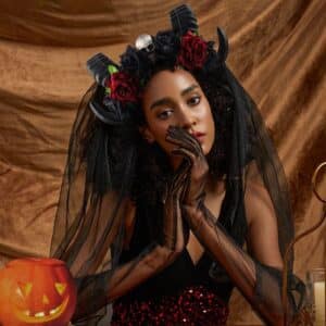 Femme déguisée pour Halloween portant une couronne de fleurs de Dia de Los Muertos sur fond marron